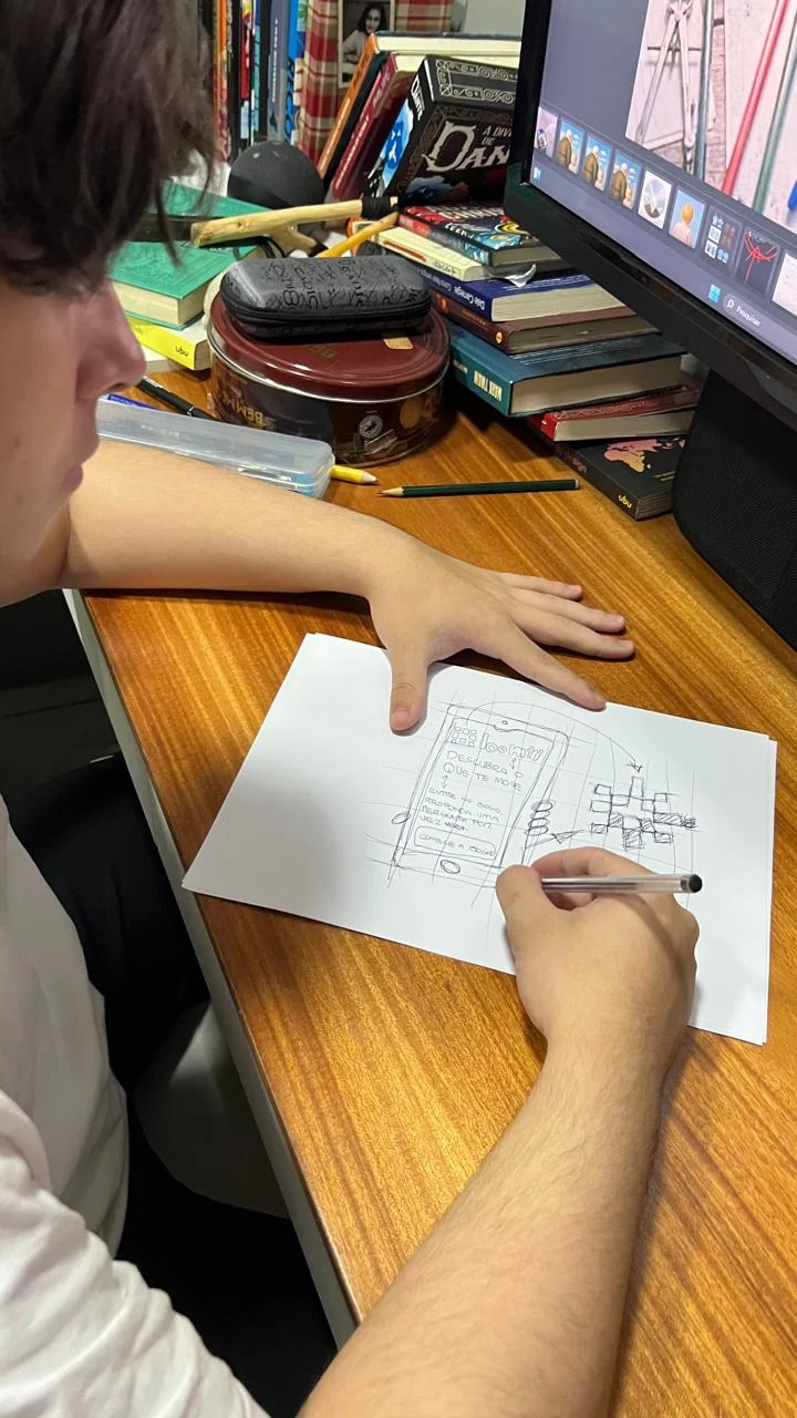 Rascunho a lápis da primeira tela do jogo da Loomty, feito à mão num papel sobre a mesa